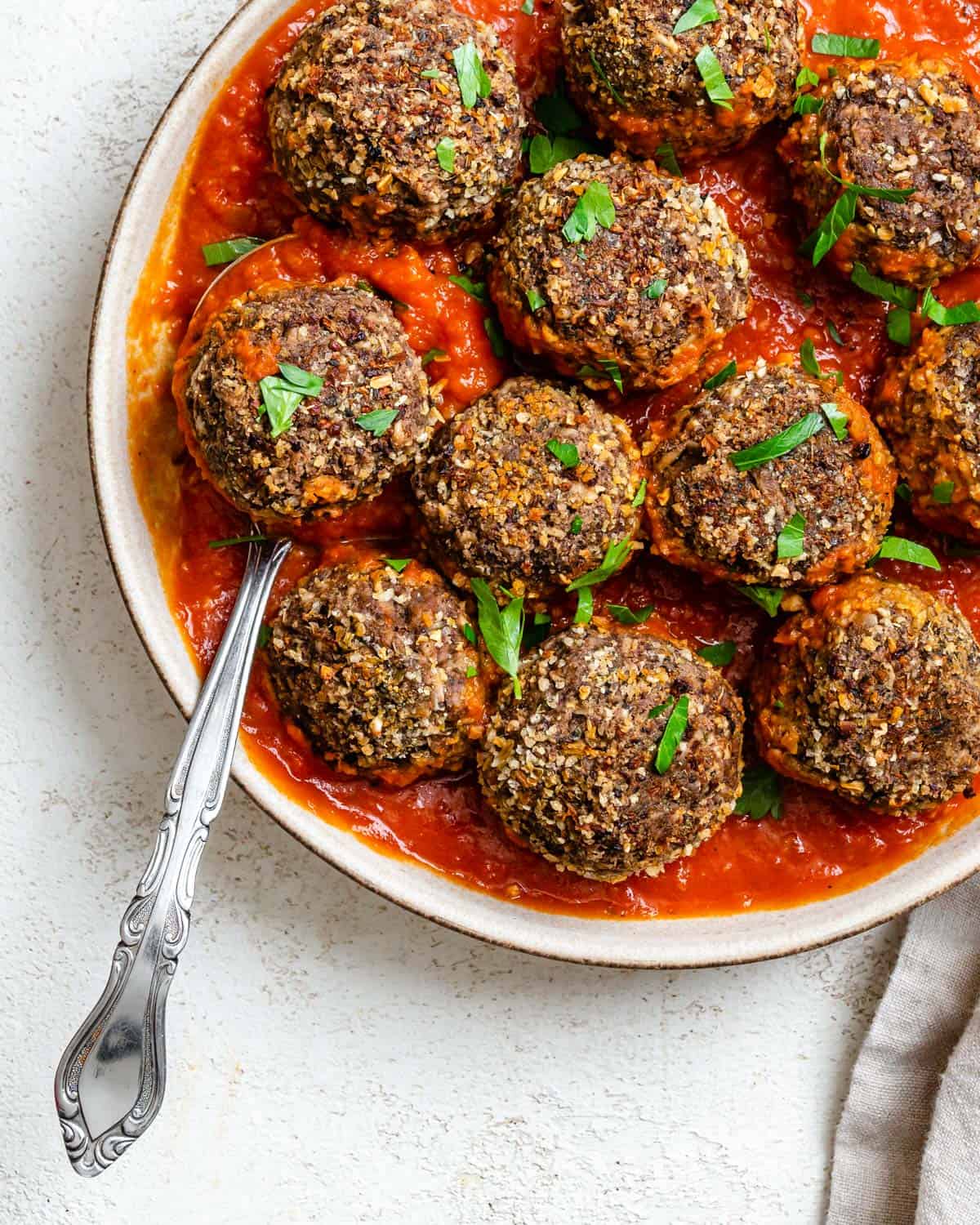 completed Easy Black Bean Meatballs spread out on plate or marinara against a white background
