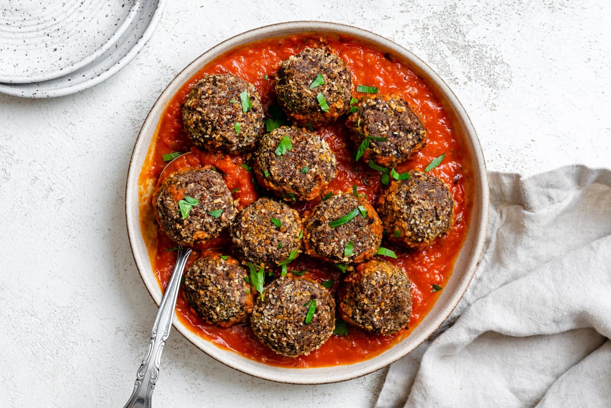 completed Easy Black Bean Meatballs spread out on plate or marinara against a white background