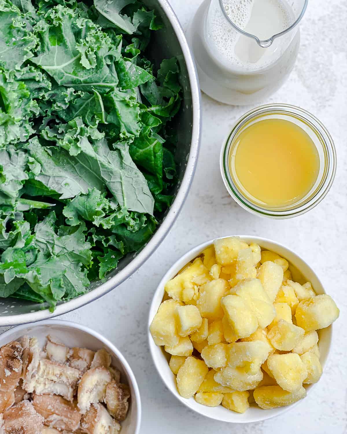 ingredients for Kale Pineapple Smoothie measured out against a white surface