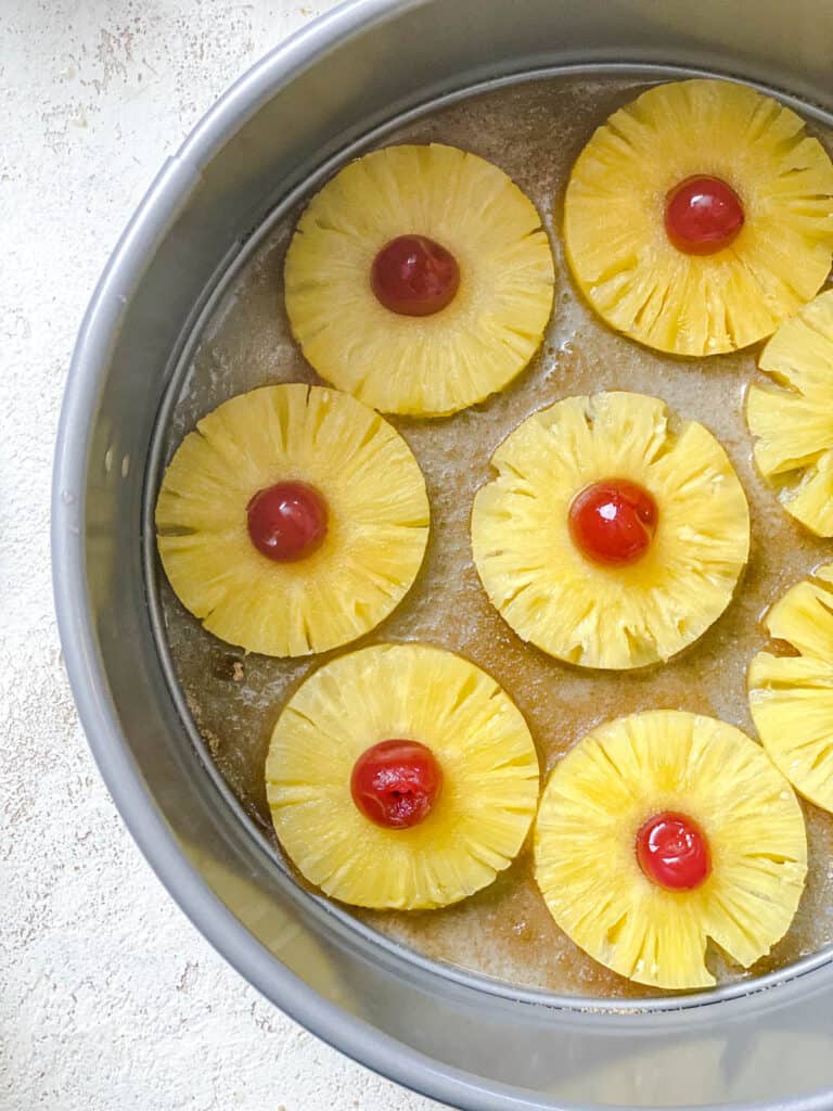 process shot of adding pineapples and cherries to pan