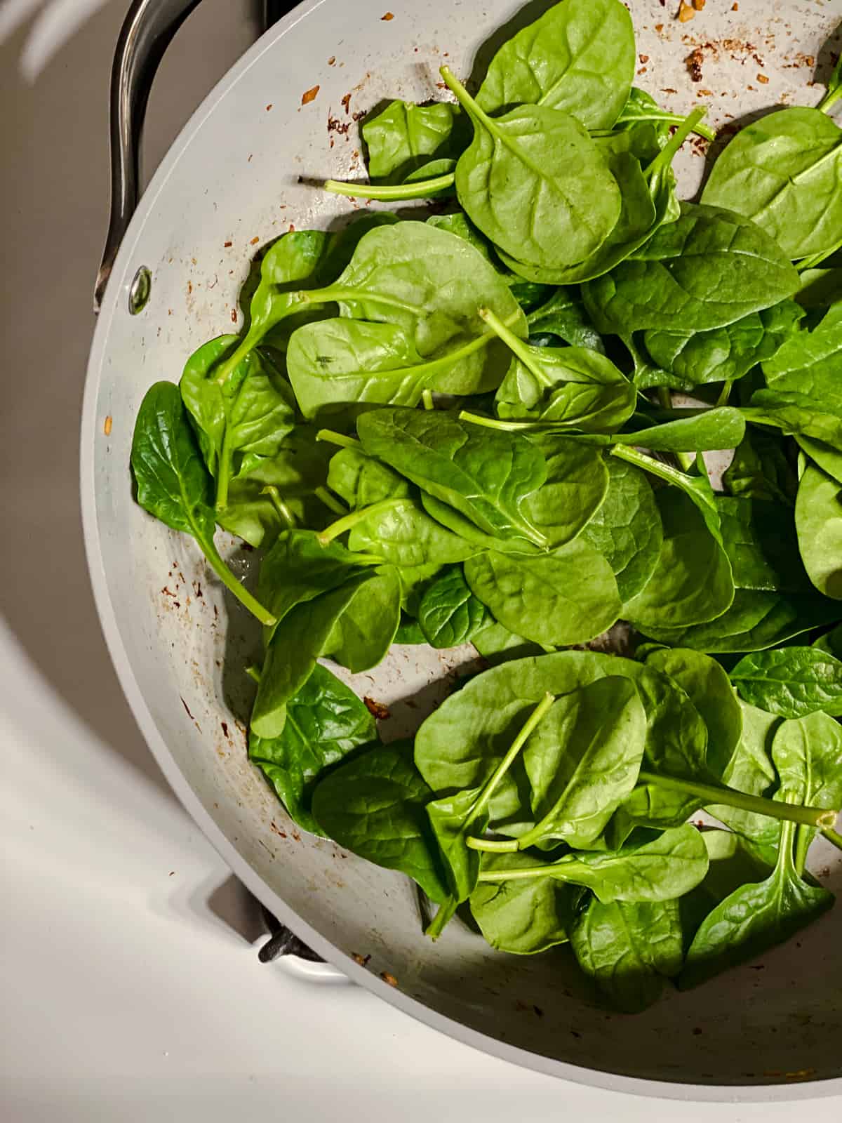 process shot of adding spinach to pan