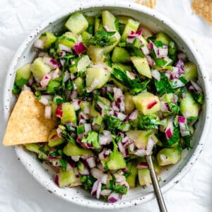 completed ingredients for Cucumber Salsa [Cucumber Pico de Gallo] added to bowl in a bowl against a white background