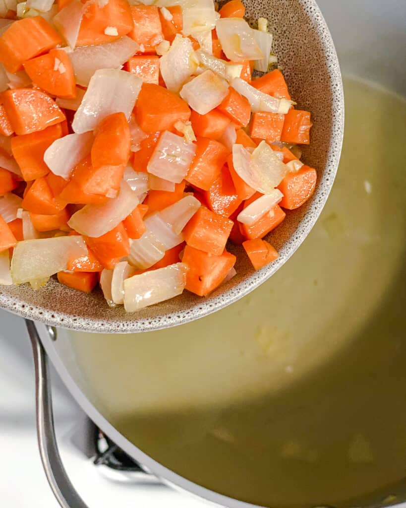process shot of carrots and onions being added to pan