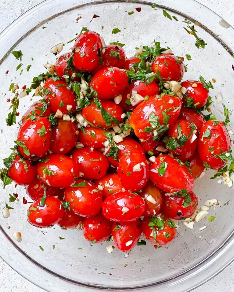 process shot of mixing Easy Roasted Cherry Tomatoes with ingredients together