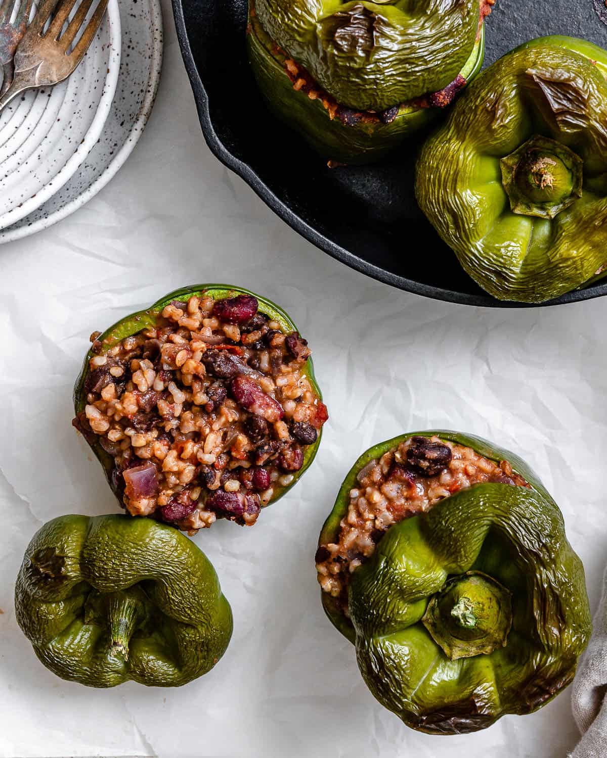 several completed stuffed bell peppers on white surface and pan