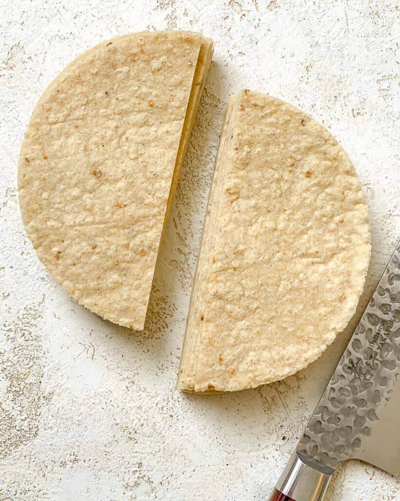 corn tortilla sliced into halves against a white surface