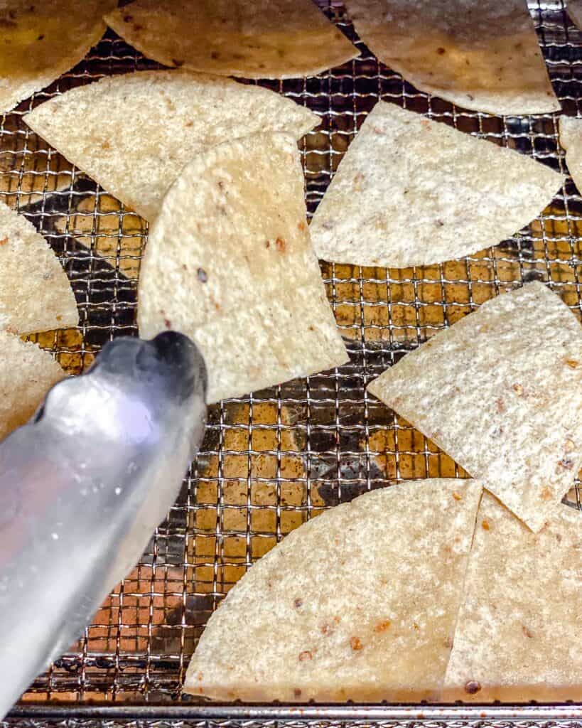 Process shot showing tortilla chips flipping on the air fryer tray