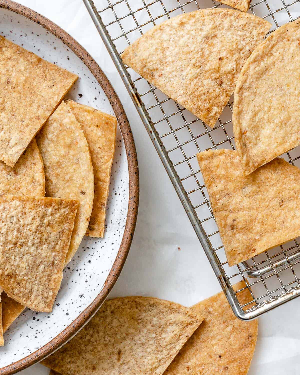 completed Air Fryer Tortilla Chips plated alongside chips against a white surface with salsa on the side