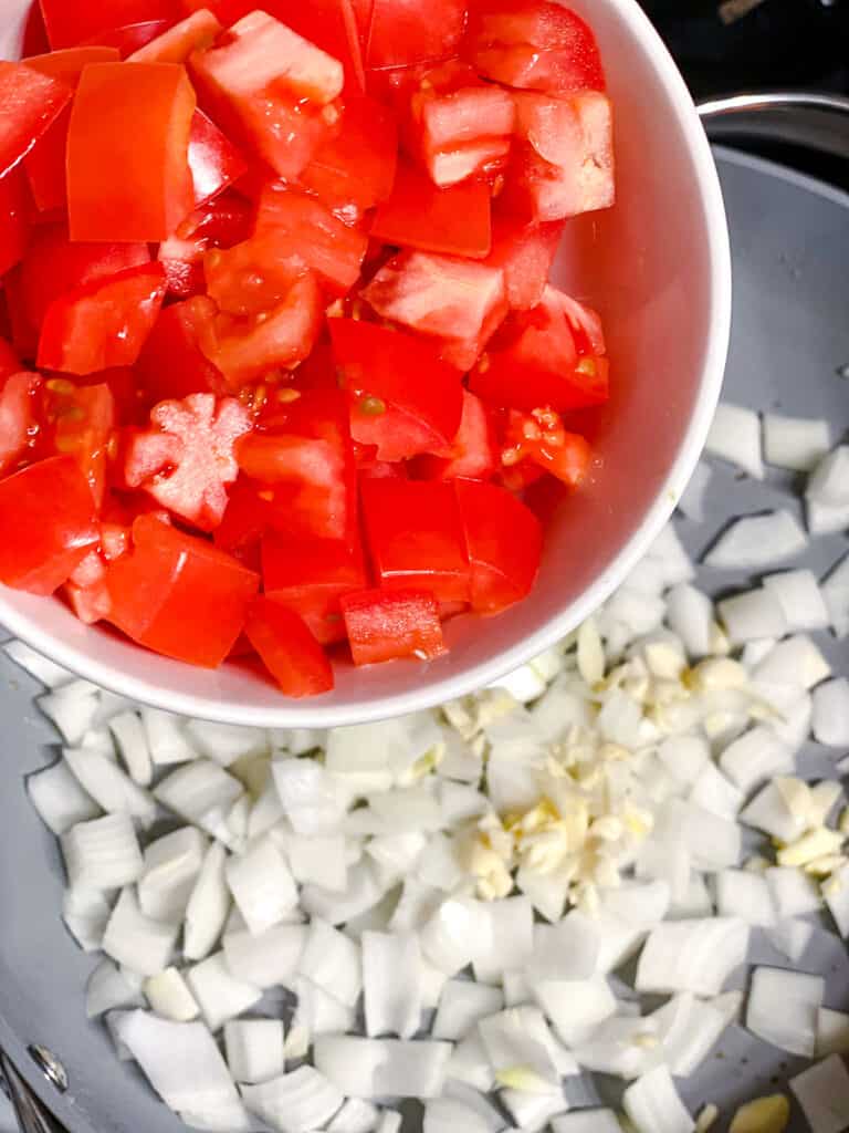 process shot of adding tomatoes to pan
