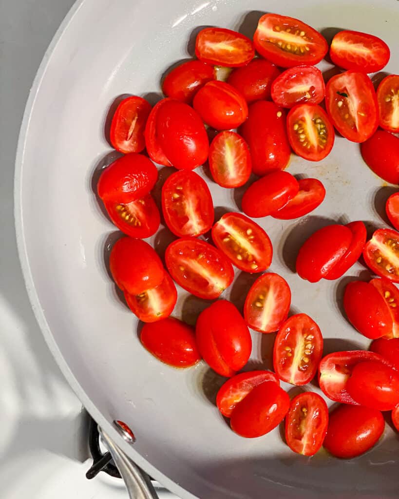 process shot of tomatoes being added to a pan