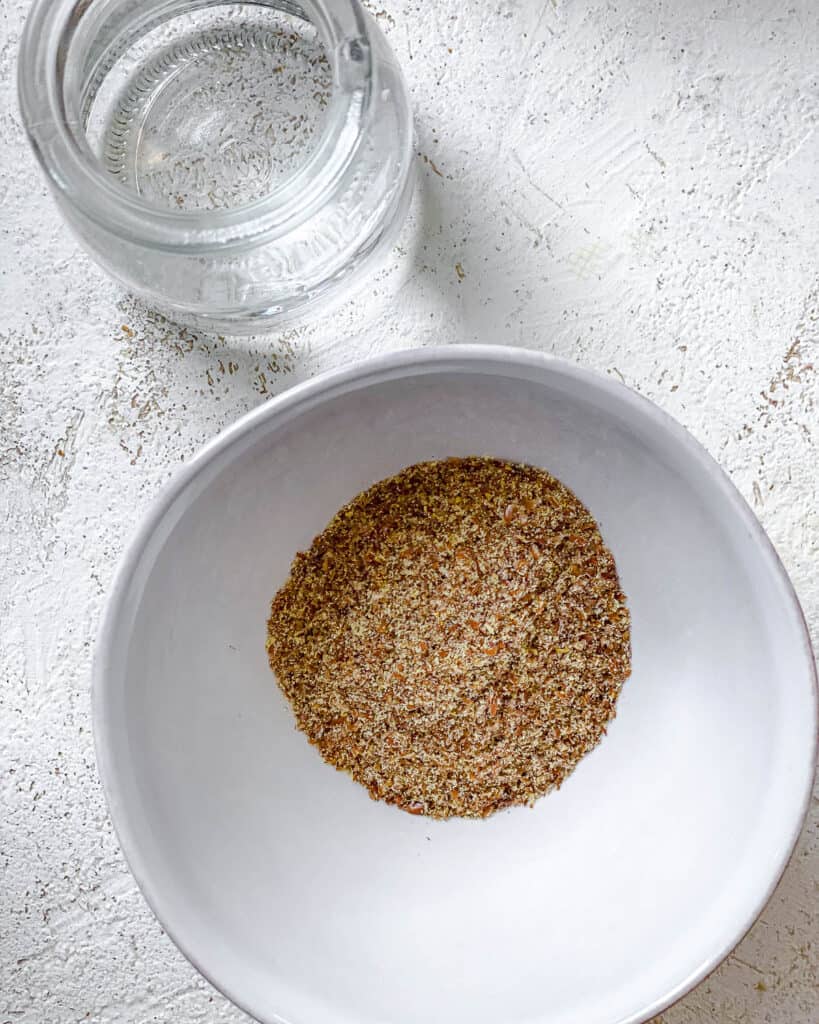 bowl of flaxseed alongside a blow of water