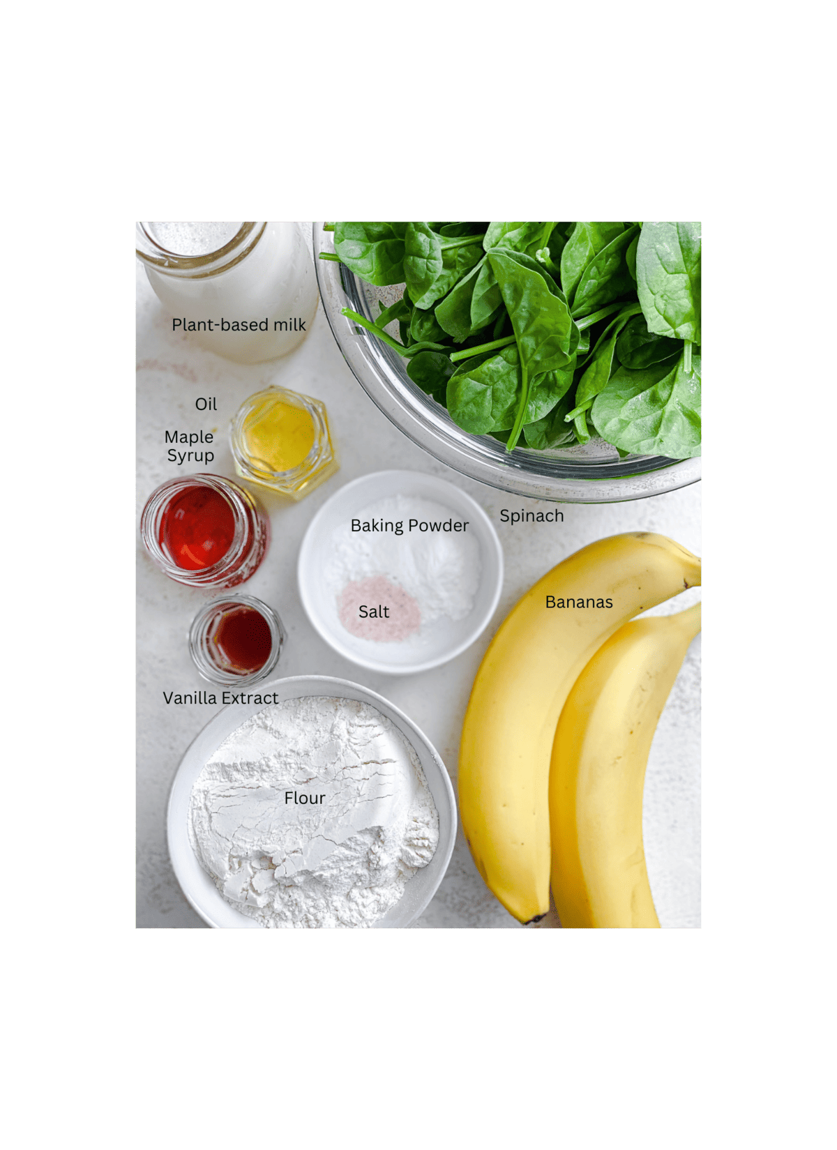 Zutaten, die für Easy Banana Spinat Pancakes gegen eine weiße Fläche abgemessen werden