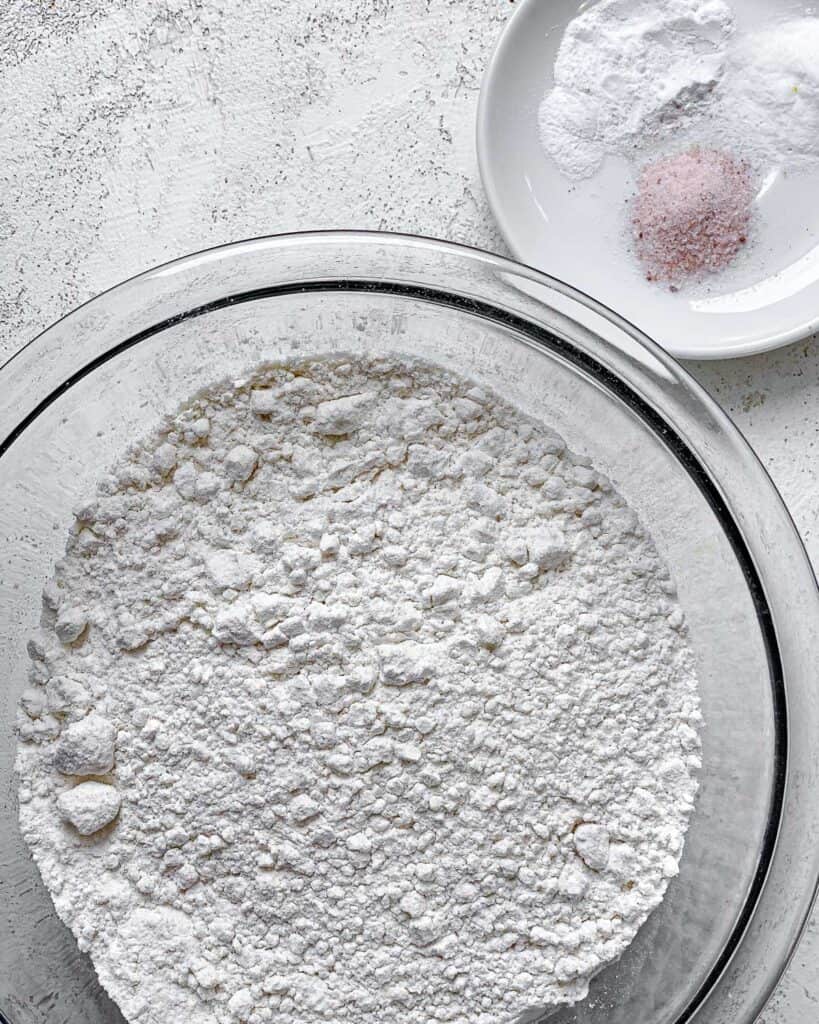 bowl of flour alongside bowl of additional salt and baking powder and soda