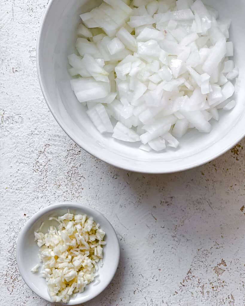 bowl of onions and garlic against a white surface