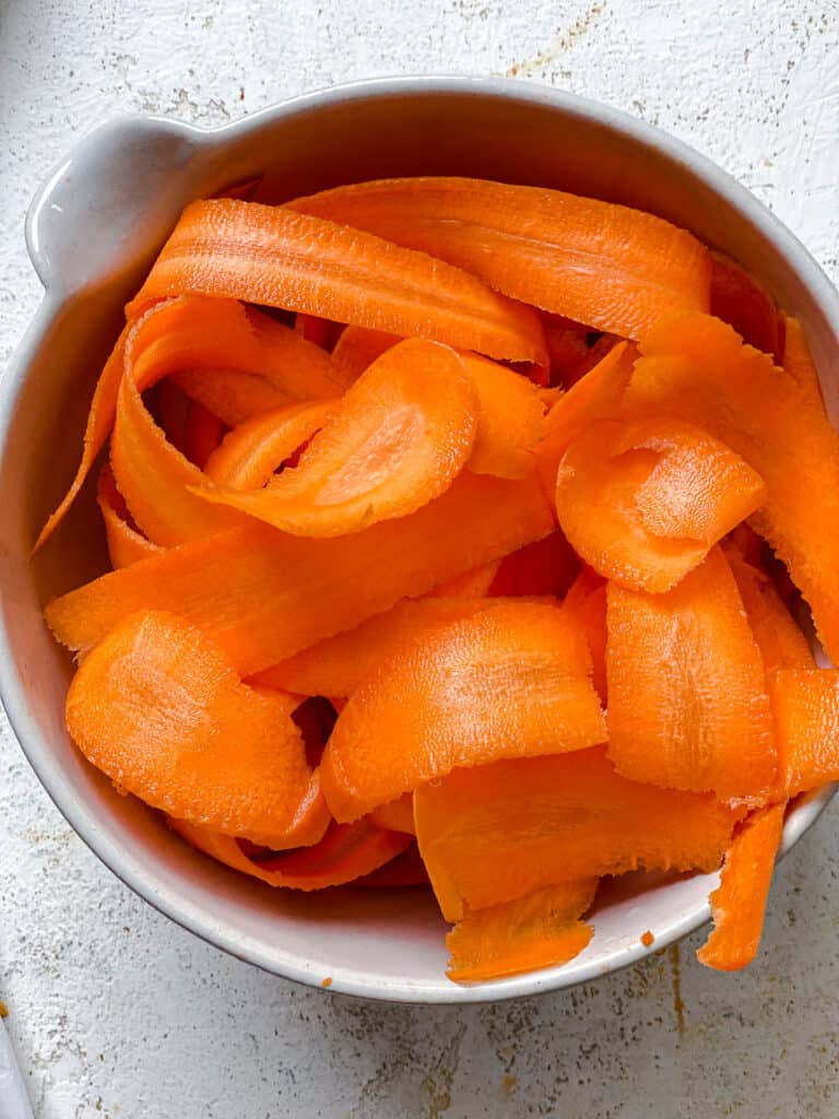peeled carrots in a white bowl
