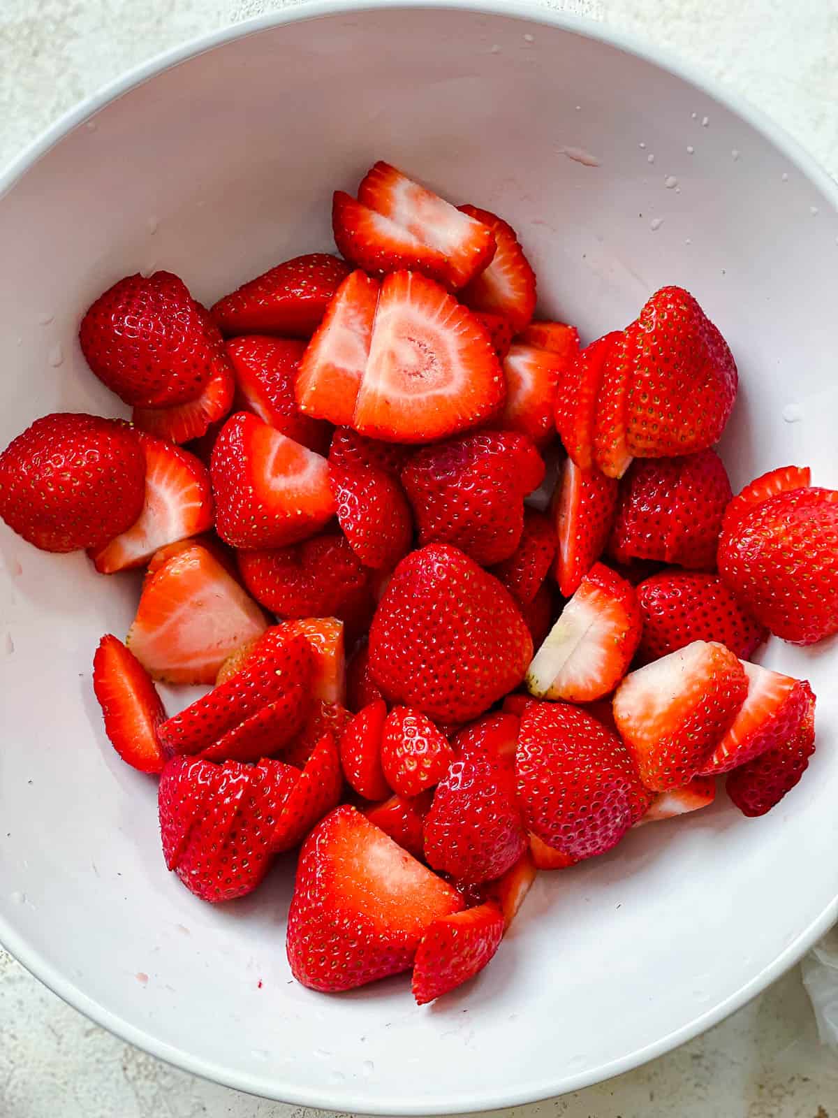 sliced strawberries in white bowl