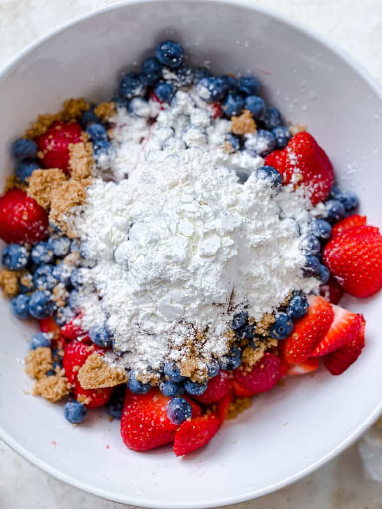 sugar and flour added to bowl of fruits
