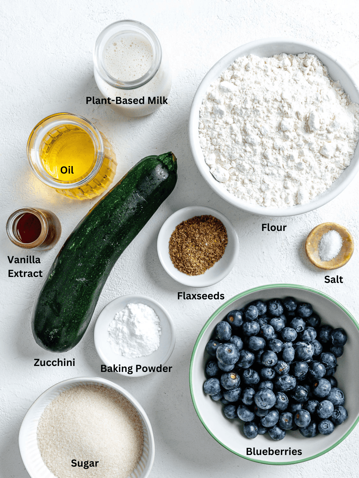 Ingredients for Blueberry Zucchini Muffins measured out on a white surface.