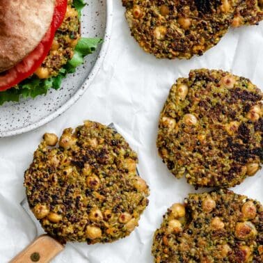 completed Quinoa Chickpea Patties on a white surface alongside a burger