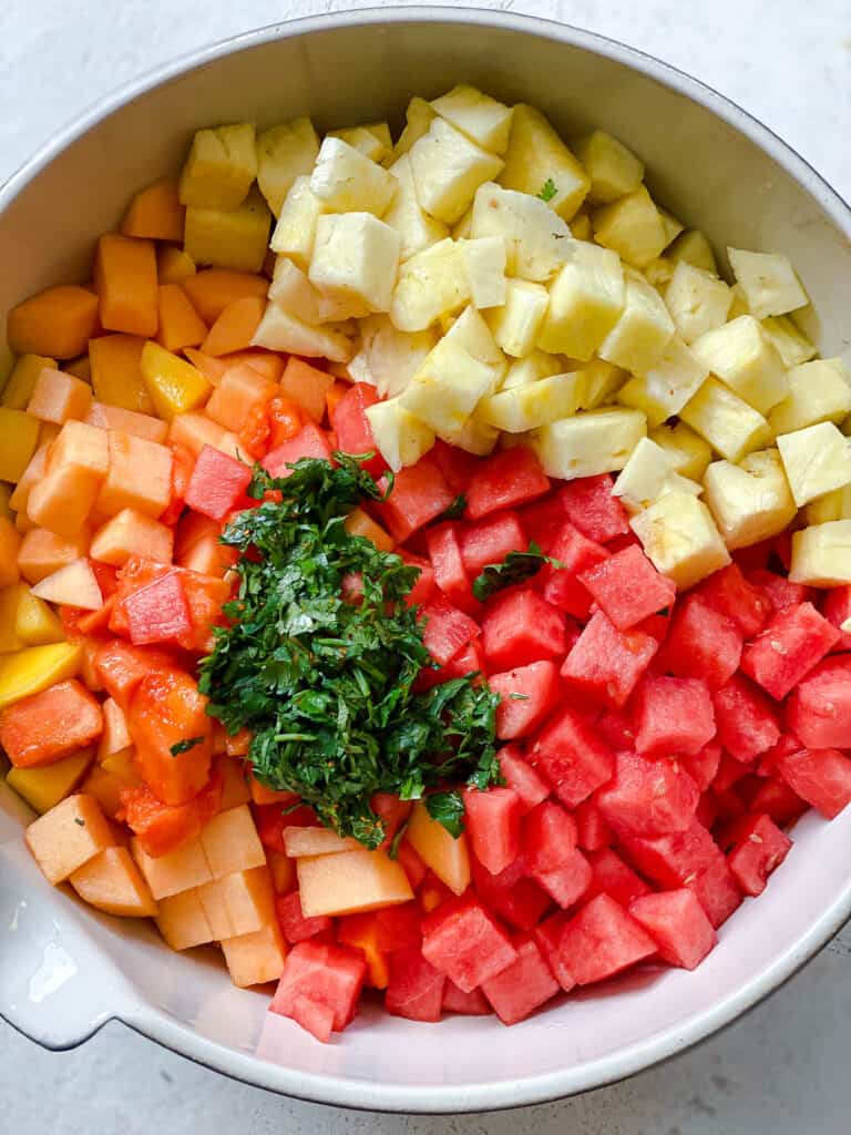 process shot showing addition of fruits and garnishes in bowl