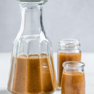 completed Miso Tahini Dressing in three separate glass jars against a light background