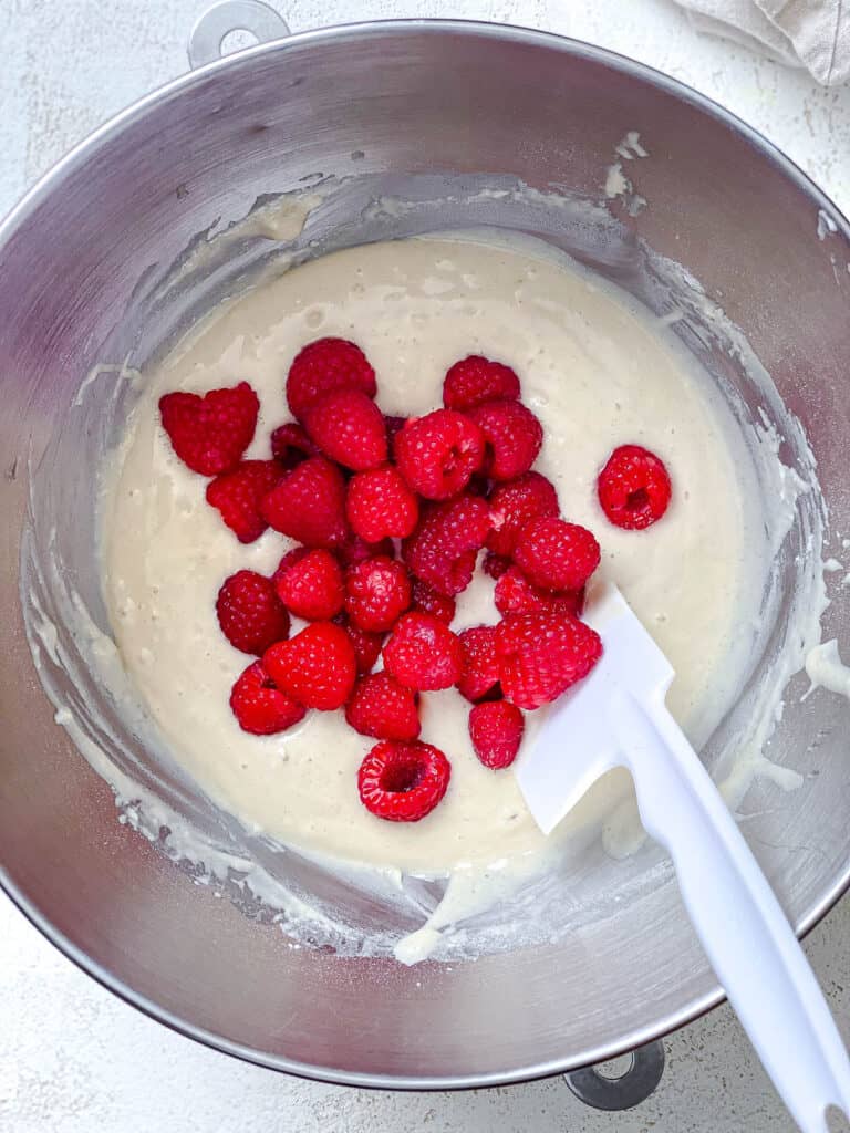 process shot of stirring raspberries into cupcake mixture