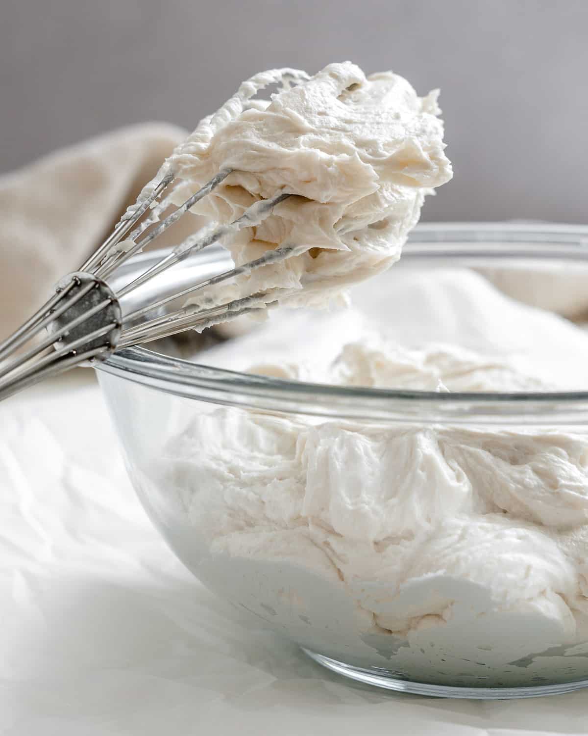 completed Vanilla Vegan Buttercream Frosting in whisk and in glass bowl 