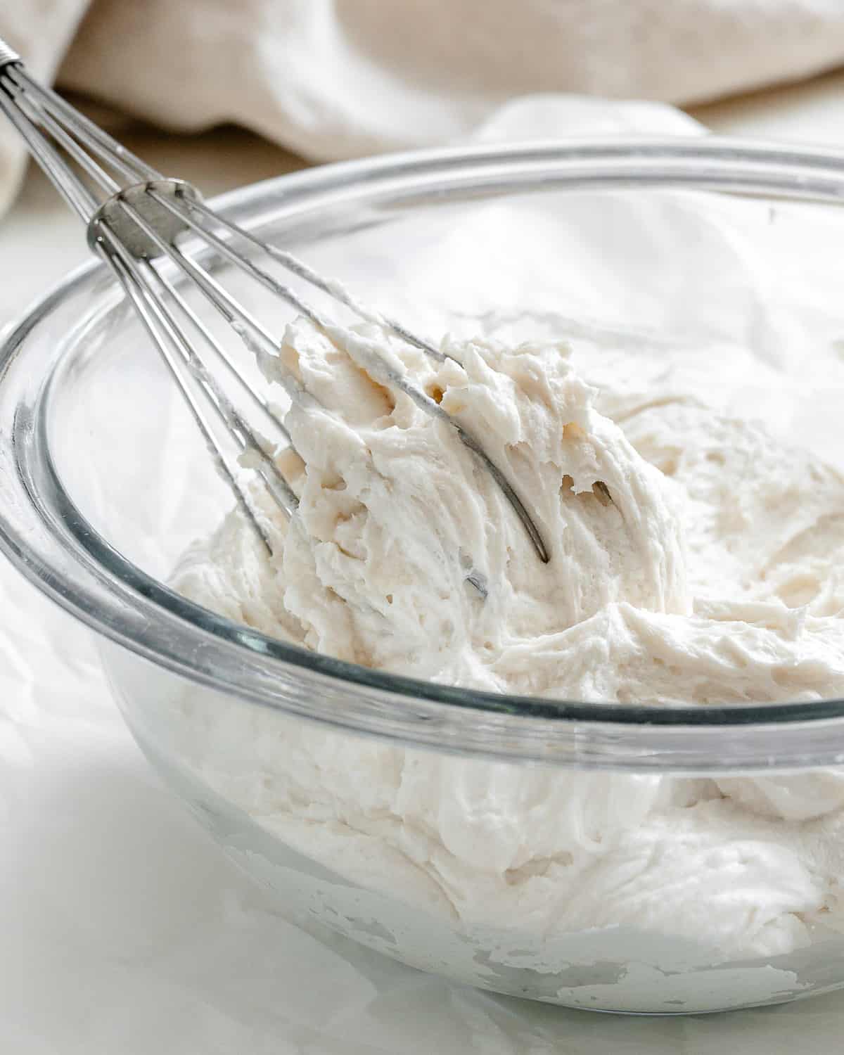 completed Vanilla Vegan Buttercream Frosting in whisk and in gl، bowl