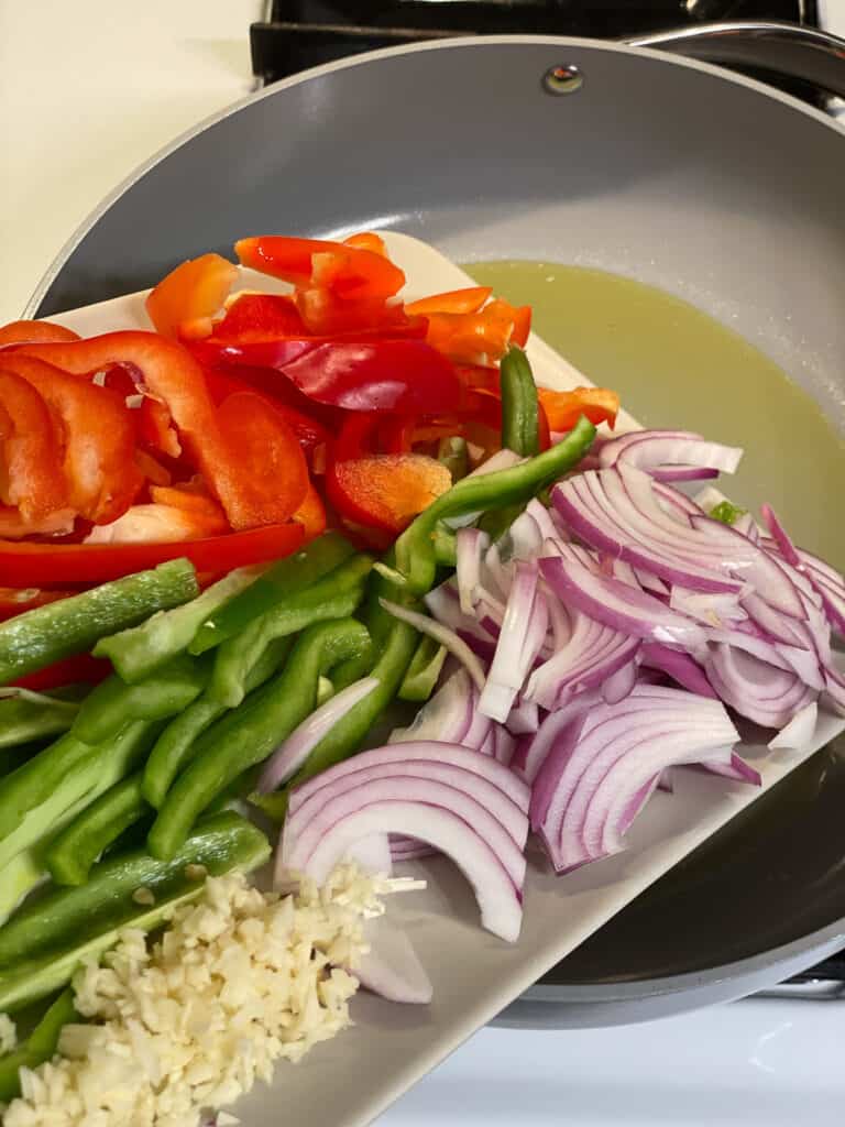 sliced vegetables for Vegan Fajita Tacos being poured into a pan