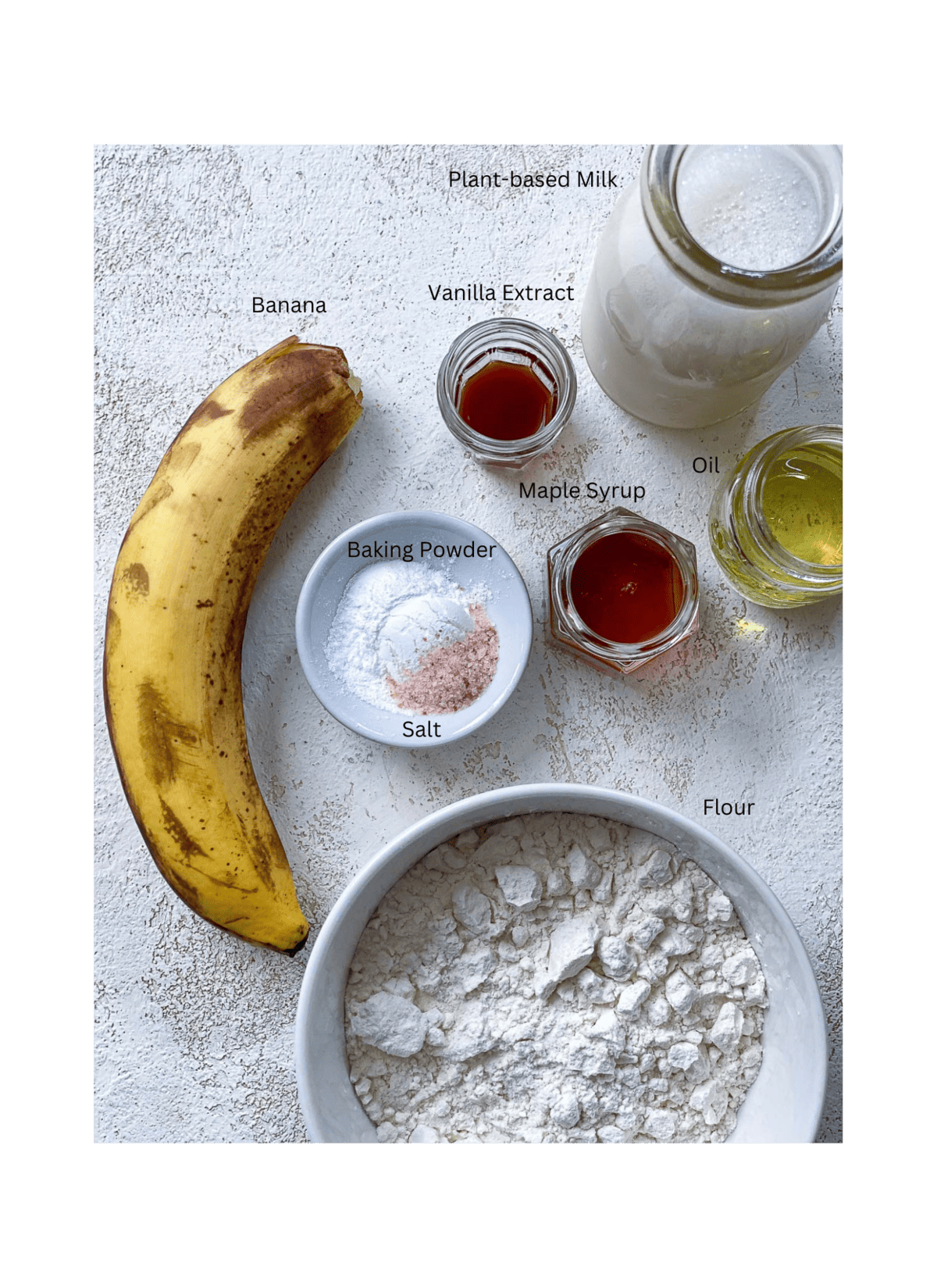 ingredients of banana pancakes spread out against a white surface