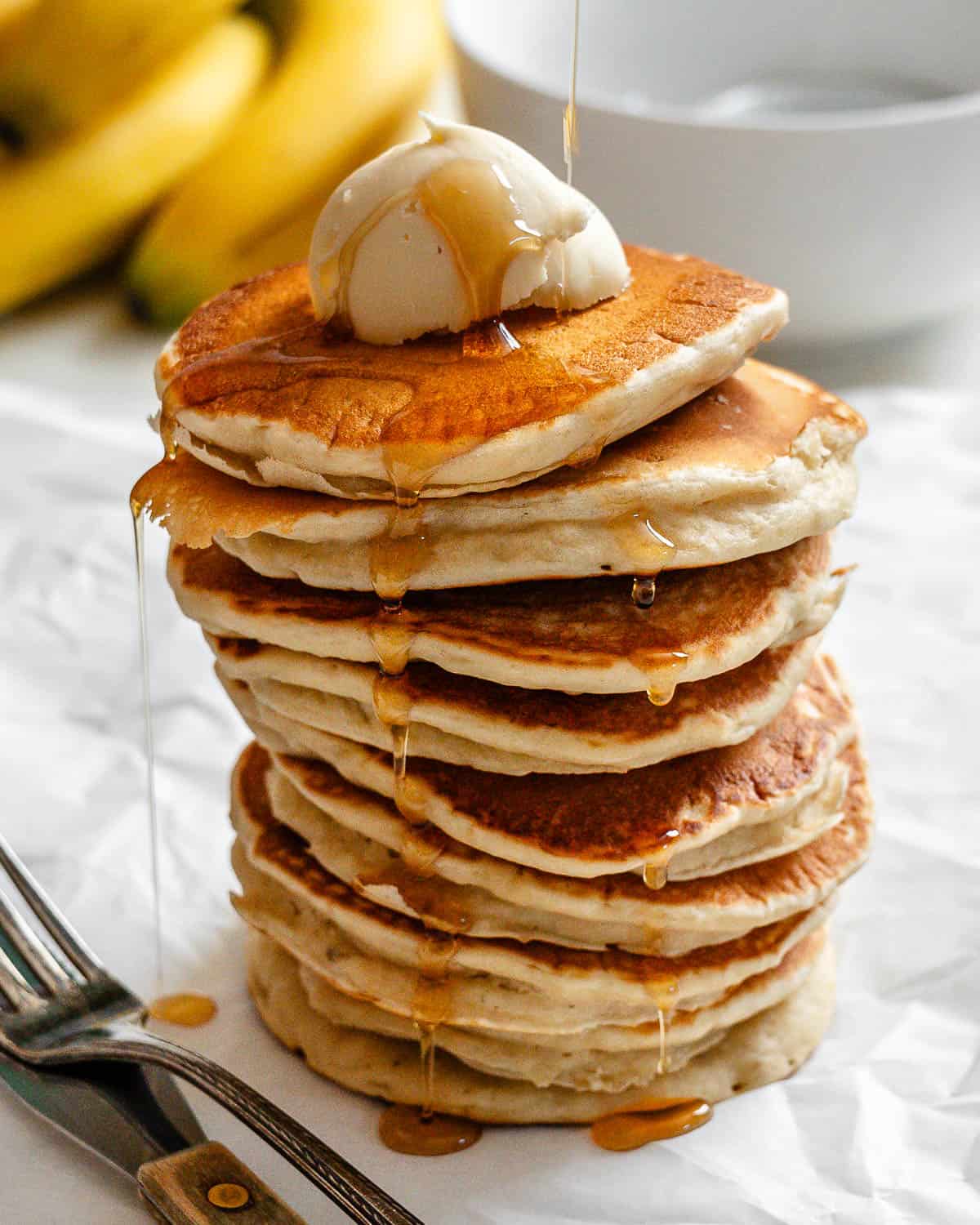 completed stack of pancakes a،nst a white surface