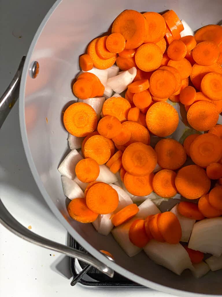 process shot of carrots and onions cooking in a pot