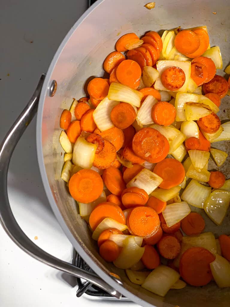 process shot of carrots and onions cooking in a pot