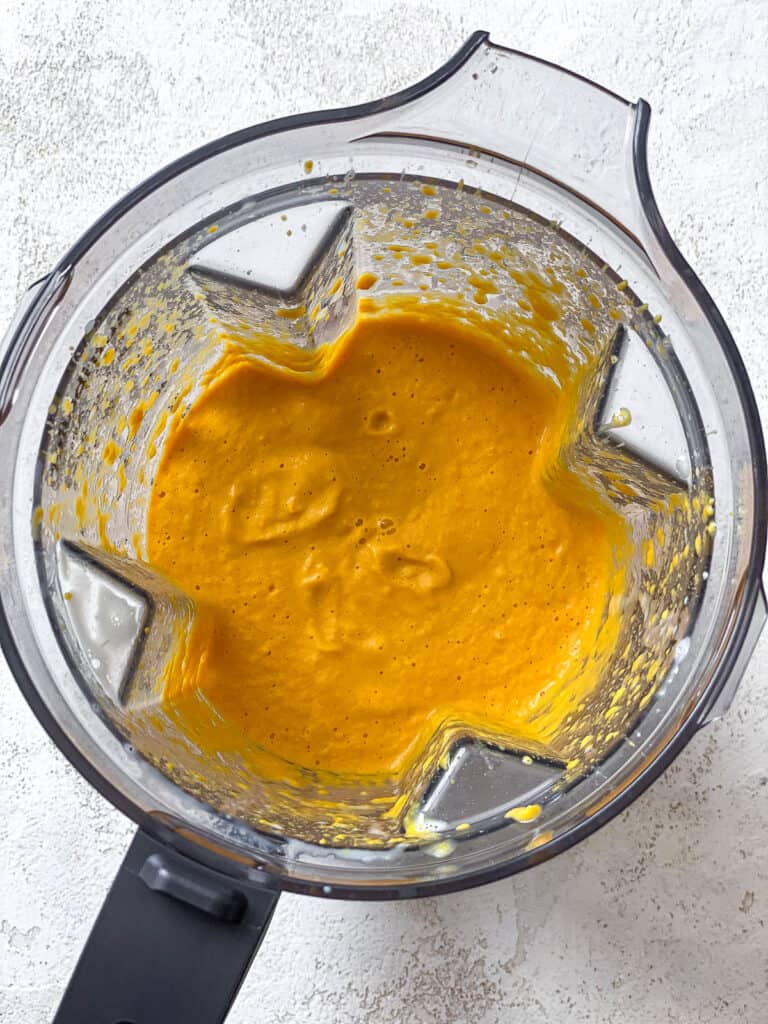 process shot of carrot curry ingredients being blended in a blender
