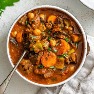 completed Eggplant Stew [With Tomatoes + Chickpeas] against a white surface