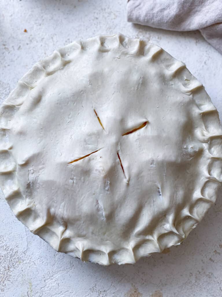 process shot showing addition of pie crust topping on top of pie