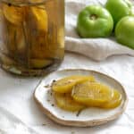 completed Quick Pickled Green Tomatoes plated alongside a jar of pickled tomatoes and raw green tomatoes