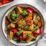 completed Easy Tempeh Stir-Fry plated on a white plate against a white surface