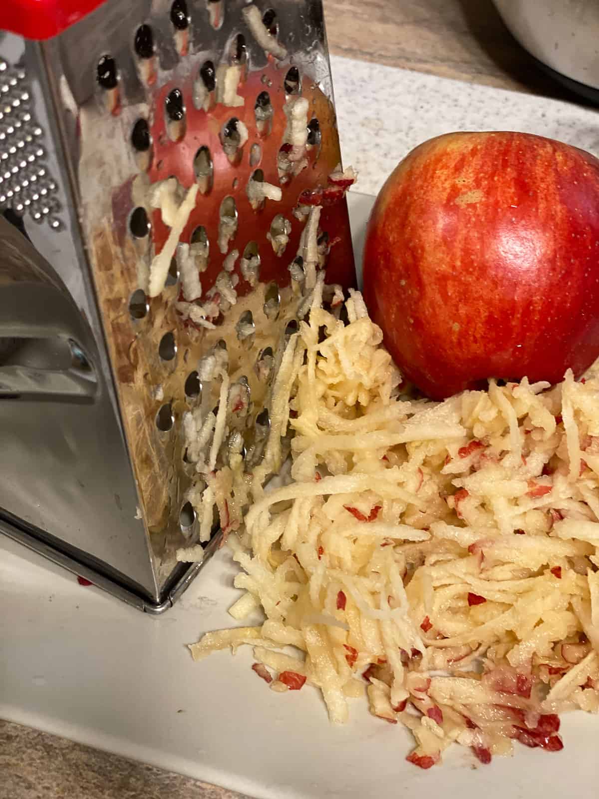 process s،t of grating apples with apple in the background