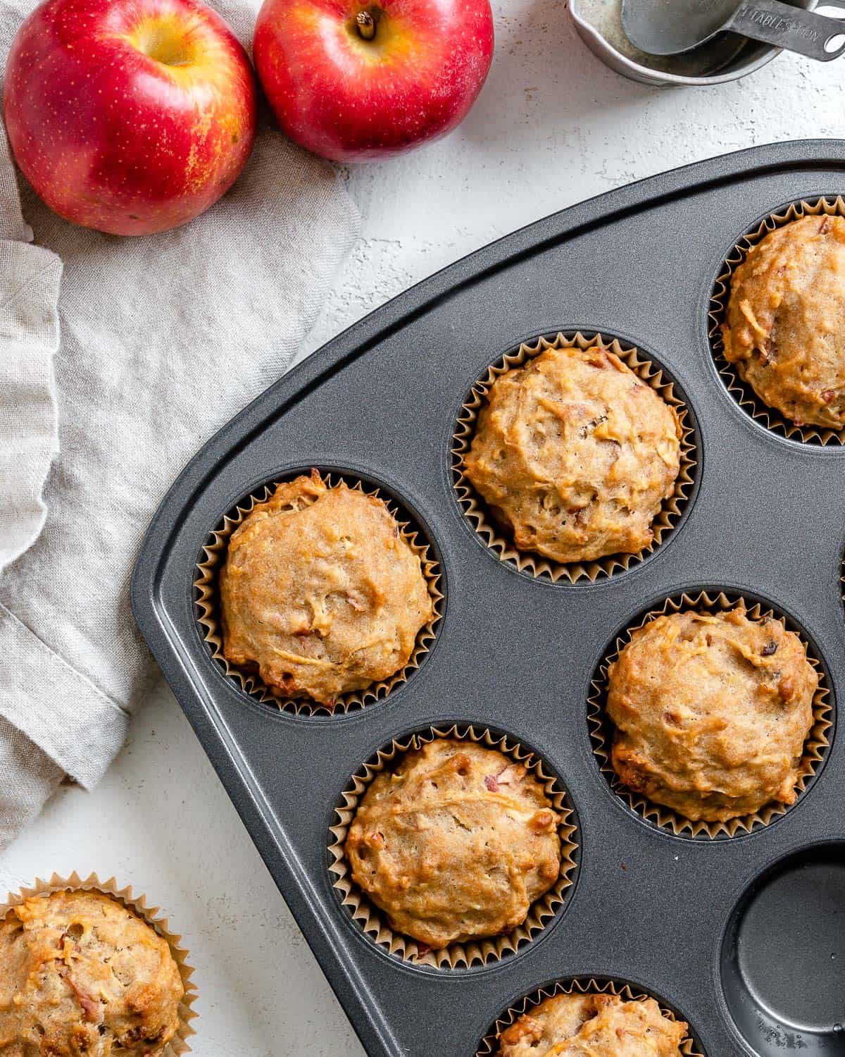 several completed Vegan Apple Muffins spread out on a white surface