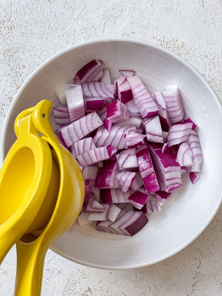 process s،t of juicing lemon onto sliced onions