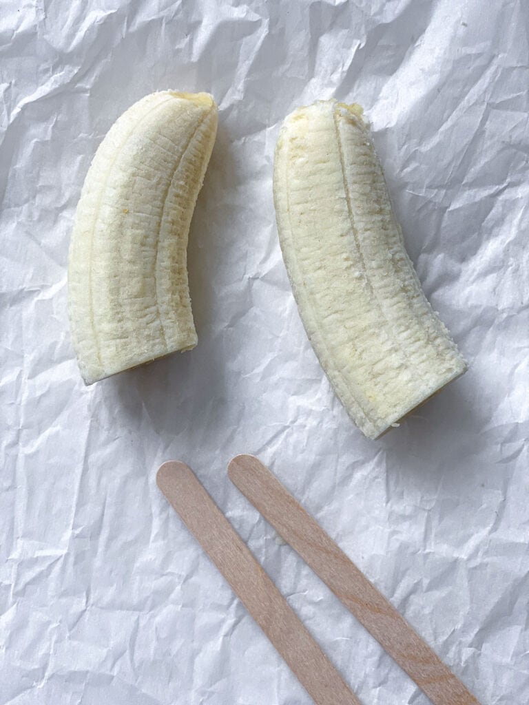 bananas and popsicle sticks on a white surface