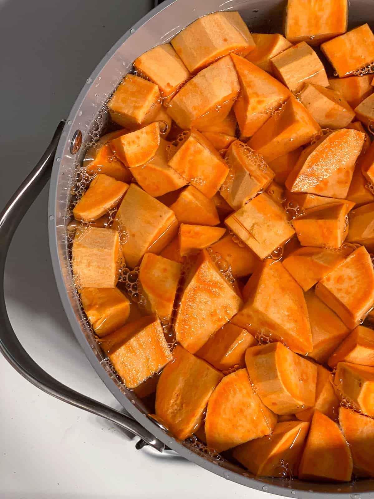 Large pot of chopped and peeled sweet potatoes submerged in water.