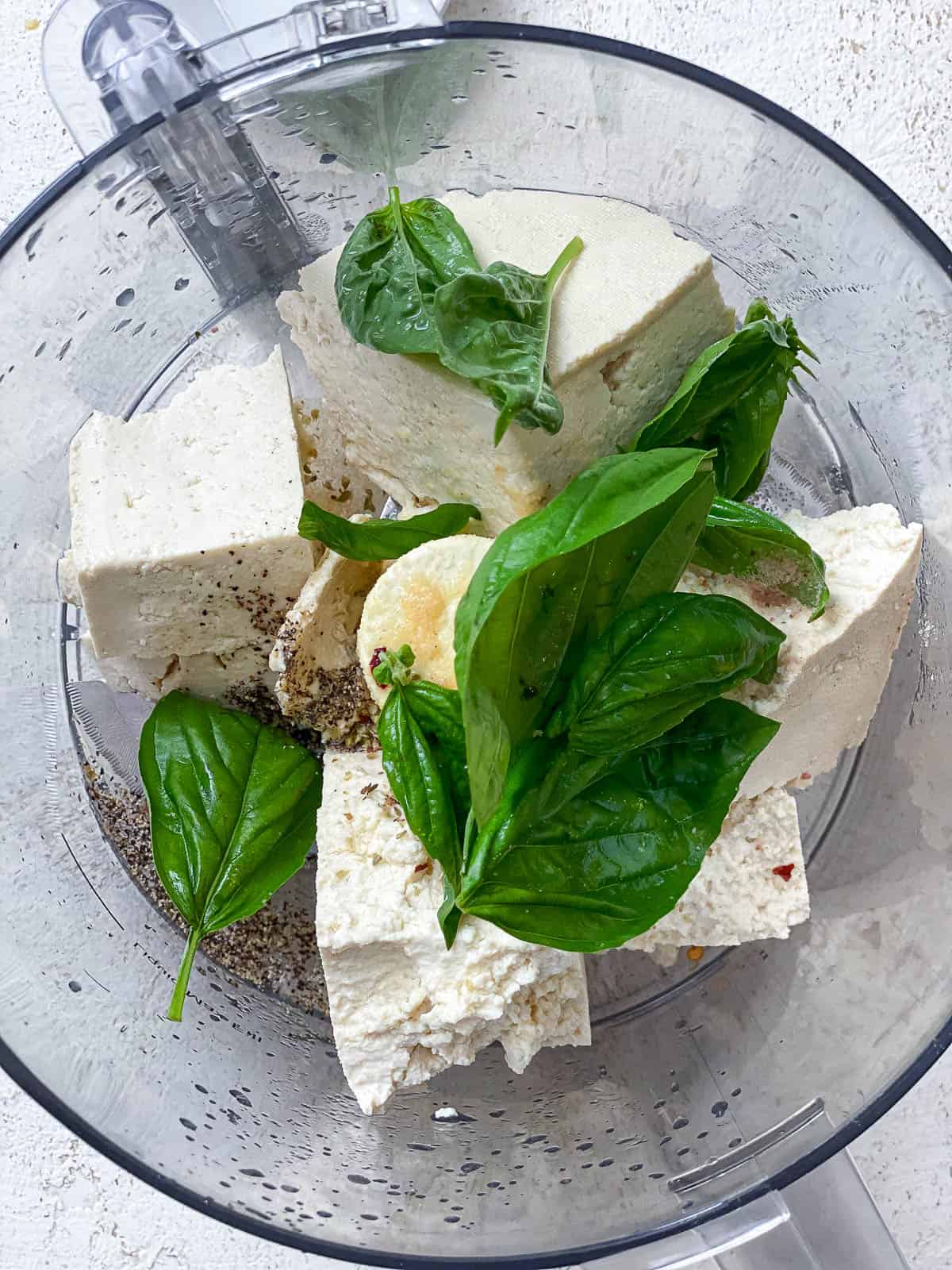 All the ingredients for Tofu Ricotta in the bowl of a food processor.