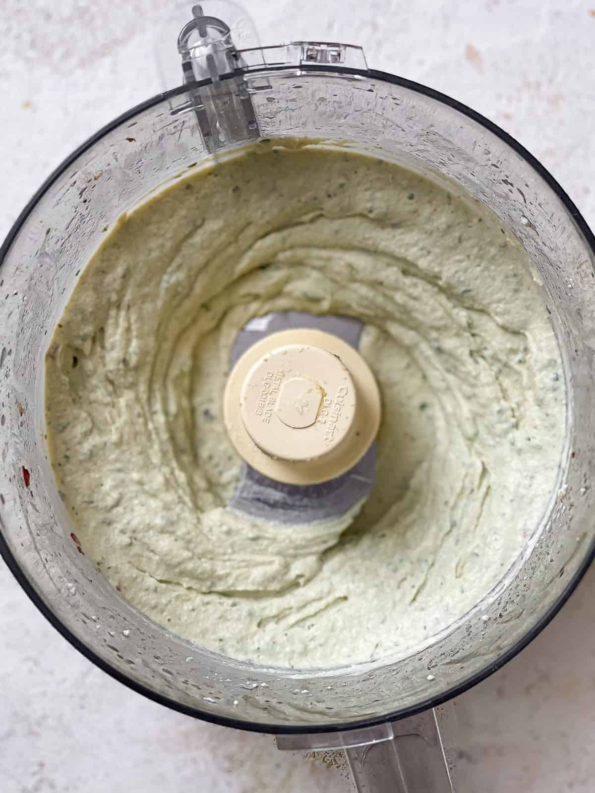 Freshly pureed tofu ricotta in the bowl of a food processor.