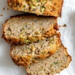 Slices of zucchini bread on white crinkled parchment paper.