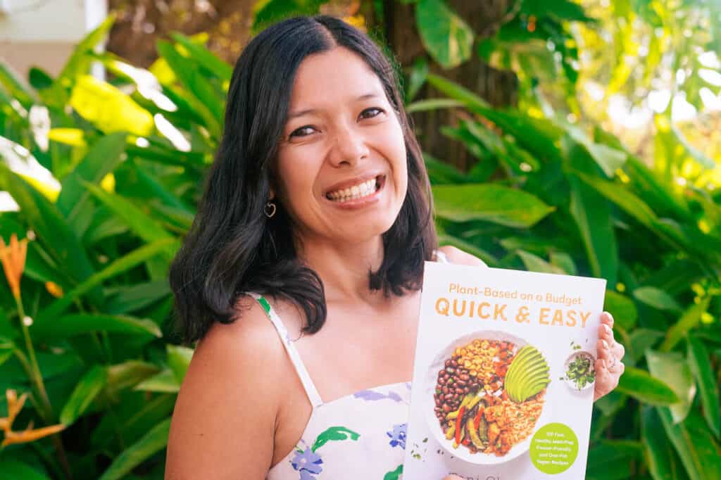Photo of Toni Okamoto, author of this website, holding her booked called Plant-Based on a Budget Quick & Easy.