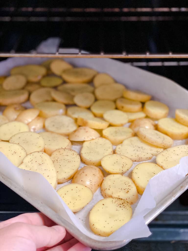 process shot of adding potatoes to oven