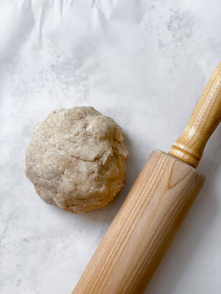 ball of dough and roller on white surface