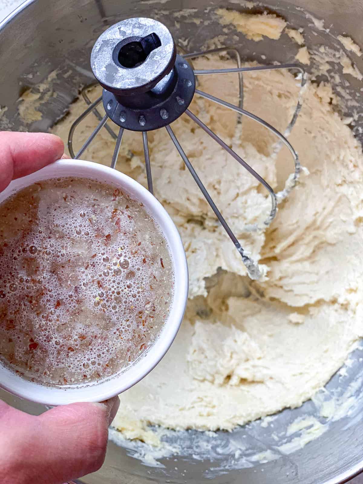 Flax egg being poured into the creamed vegan butter and sugar.